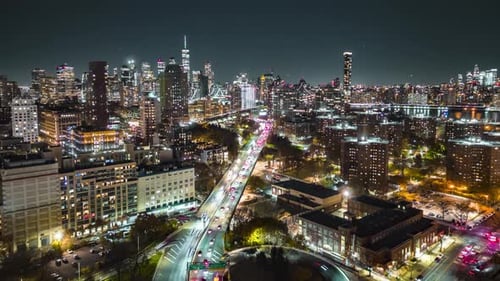 Forwards Fly Above Modern Metropolis with Illuminated Skyscrapers and Busy Highway