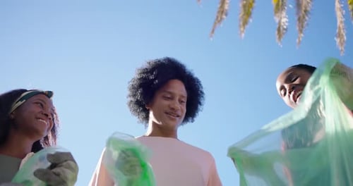 Amigos afroamericanos facturando bolsas verdes después de limpiar el parque, enguantados y celebrando