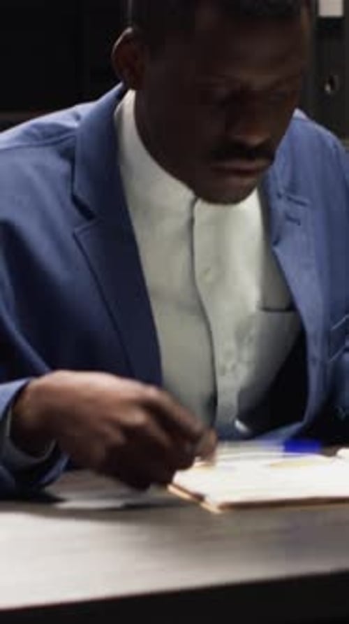 Man Reviews Documents With Pen in Office