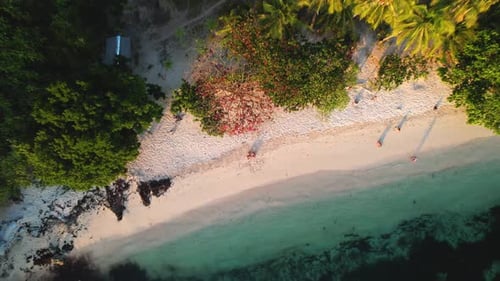 4K drone video of a couple sitting on a white sand beach on a tropical island in Palawan, Philippine