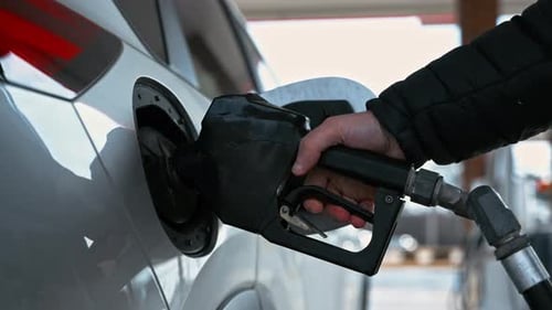 Person Refueling a Car at Gas Station Using Fuel Pump Nozzle During Vehicle Fueling