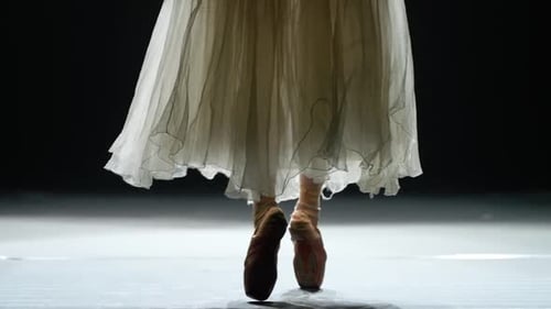 Elegant Woman in a White Tutu Dance Ballet and Balancing in Pointe Shoes View of the Legs Dark