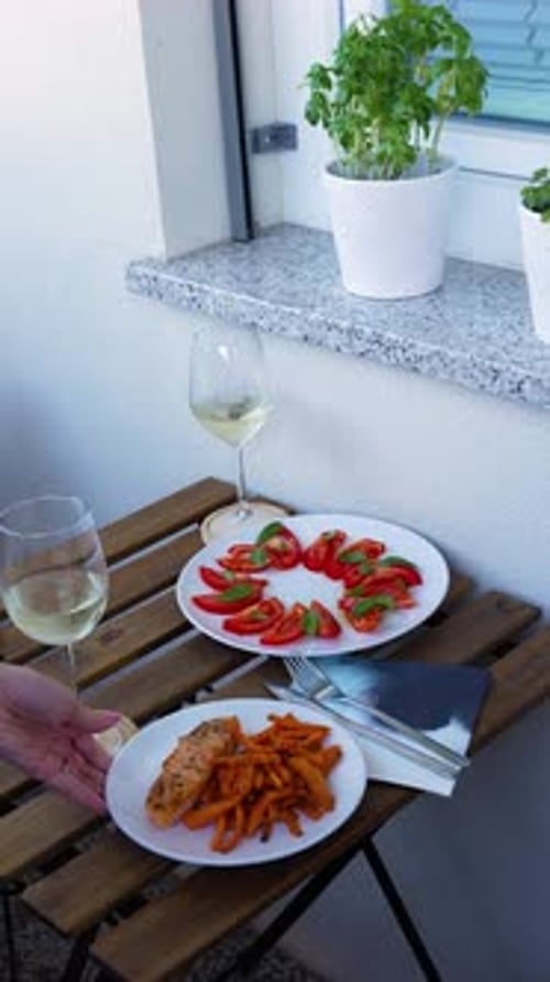 Two Glasses Of White Wine, Plate Of Tomato And Basil Salad, And Dish Of Salmon With Fries On Wooden