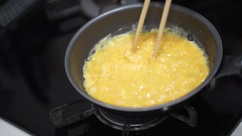 Eggs Cooking in a Pan with Chopsticks