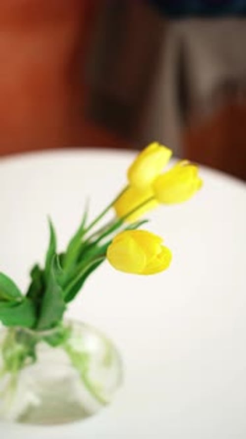 Bouquet of yellow tulips in a transparent glass vase stand on a white table