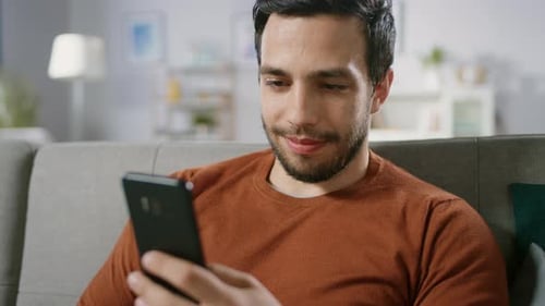 Man Relaxing on Sofa Browsing Mobile Phone