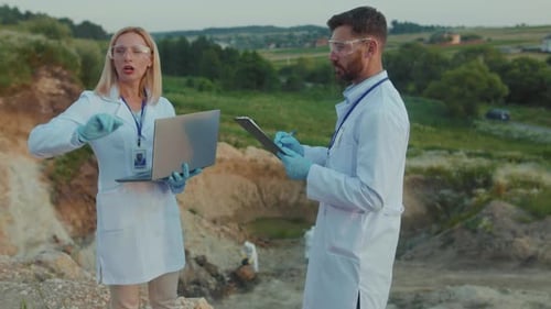 Experten für Outdoor-Ökologie verwenden Laptop in Schutzkleidung, arbeiten an Land, Hilfe, sprechen Chemikalien und