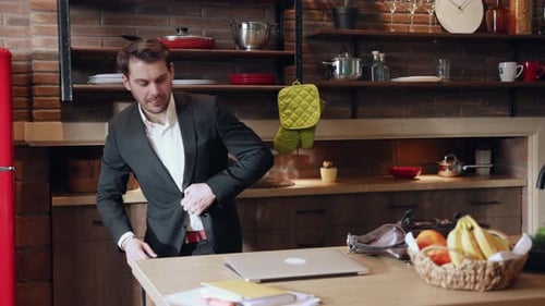 Man Celebrates Success with Laptop at Kitchen Island