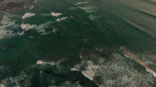 Aerial downward tilt view of breaking green swell in Costa Rica bay