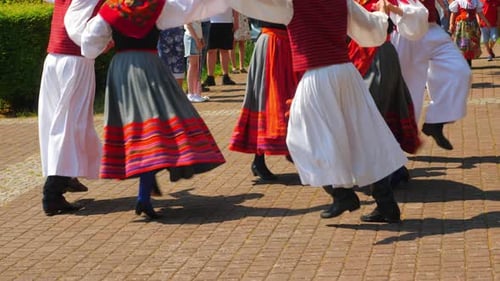 folk dancers jumping in slow motion, belt down view, colorful dresses