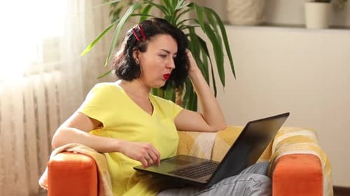 Woman Using Laptop Sitting Indoors in Orange Chair