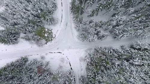 Drone view of forest road intersection between snow covered trees. Crossroads and the necessity to c