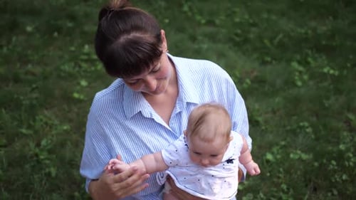 Loving Mother Holds Baby in Green Outdoors Setting
