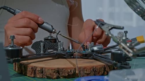 Femme faisant un travail de fer à souder et testant un drone