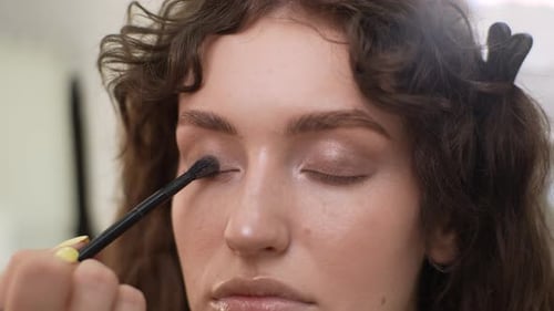 Closeup Face of Attractive Young Woman Being Given Applying Eyeshadow with Glitter in Beauty Salon