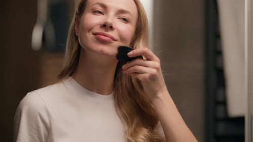 Woman Uses Gua Sha on Face in Bathroom