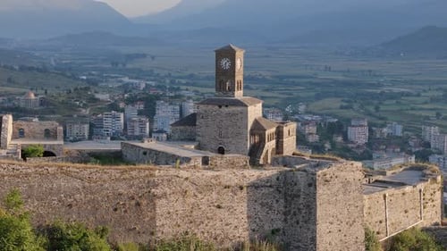 Castle of Gjirokastra clock tower at Sunrise, Aerial drone orbit view with City in background