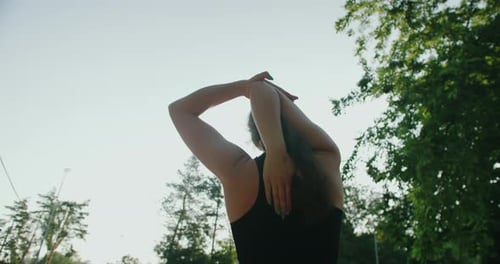 Woman Stretching Arms in Urban Park Setting
