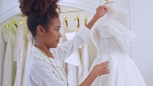 African American female designer designing bridal gown in wedding studio.