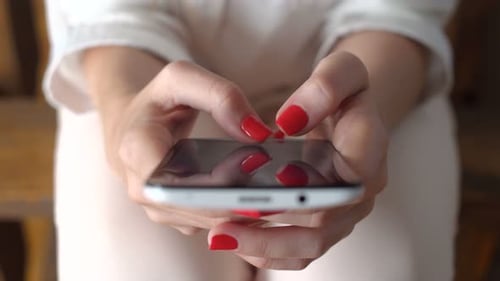 Woman Typing on Smartphone with Red Nail Polish