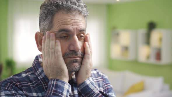 Mature man looking tired and sluggish looks at himself in the mirror ...