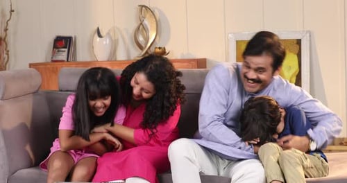 Happy Family Laughing Together on Couch at Home