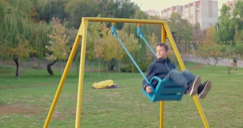 Boy Swinging on Swing Child Having Fun Playing in Outdoor Public Playground