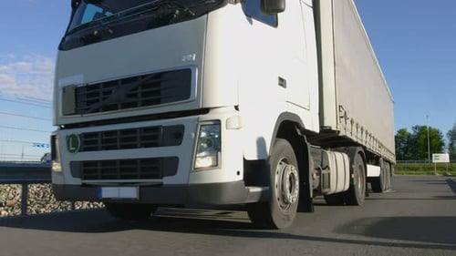 White Semi Truck with Cargo Trailer Drives Out of Industrial Loading Area.