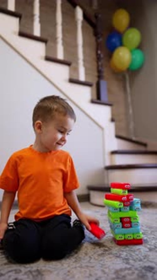 Un
hermoso niño pequeño sentado en el suelo construye una torre de bloques. Lindo niño juega en casa.