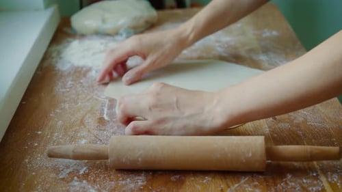 Hands Rolling Dough with a Wooden Rolling Pin
