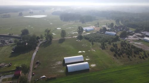 Sunny morning over white arched hall in field steam atmosphere aerial