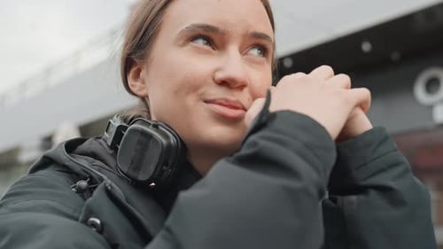 Outdoor Thoughtful Woman City Girl with Headphones Pauses Female in Winter Coat Gazes Into Distance