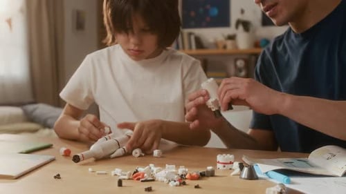 Father and Son Constructing Toy Space Rocket Model at Home