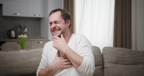 Man Laughing hysterically while sitting on couch