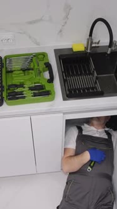 Male Plumber Repairing Sink Pipes in Kitchen Top View Vertical Video