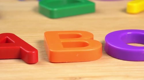 Colorful ABC Alphabet letters rotate on a wooden background. The concept of learning, school