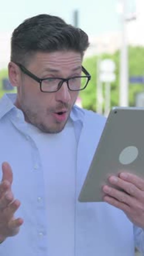 Man Expressing Shock While Looking at Tablet Screen