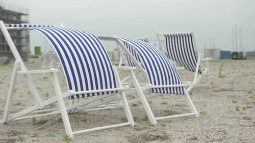 Couple of Sun Chairs on an empty beach, waving in the wind.