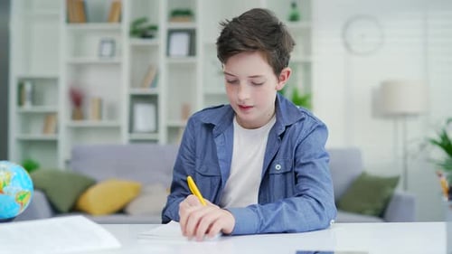 Boy Writes at Desk in Bright Home