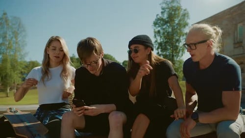 Stylish Cool Teenagers Chilling on the Benches in the Park, Using Smartphone. Two Girls and Two Boy