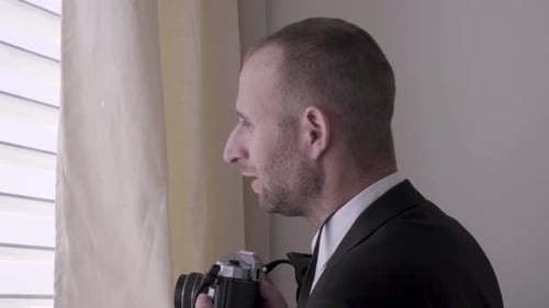 Man in Suit Taking Pictures by Window