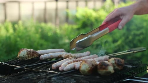 Barbecue Concept Hand dreht Grillwürste mit einer Zange um