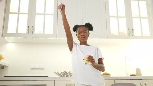 Young Woman Dancing in Bright Kitchen With Juice