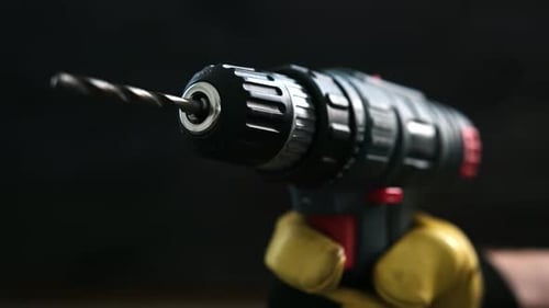 Closeup View of a Hand Holding a Cordless Drill at a Worksite