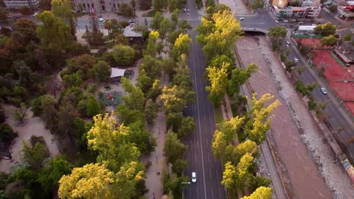 Vehicles passing along a road next to a park in the center of a large city. Aerial view