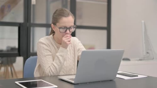 Coughing Young Woman Using Laptop in Office