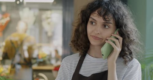 Cheerful Young Lady Flower Shop Manager Talking to Customer on Mobile Phone Discussing Order While