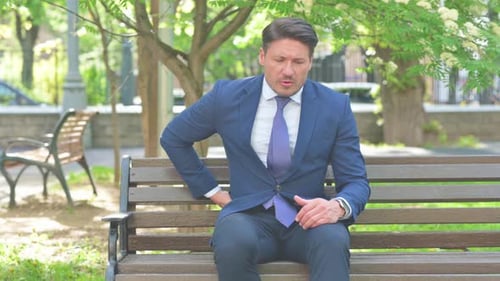 Man in Suit Sitting On Bench in Park