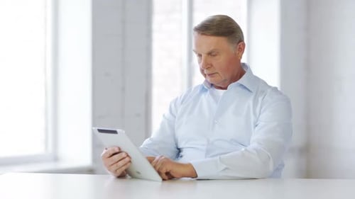 Senior businessman browsing on tablet computer at home for school and education