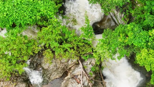Stunning tropical waterfall amidst lush green forest, captured by drone.